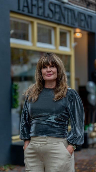 Trots voor Tafelsentiment & Het Lokaal Sigrid Huiskes tevreden voor de gevel van Tafelsentiment & Het Lokaal na de opening op 17 november